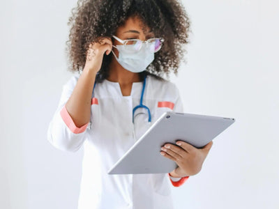 Demonstrating charlie's hair and beauty - an african american female doctor wearing glasses and a face mask uses a tablet ...
