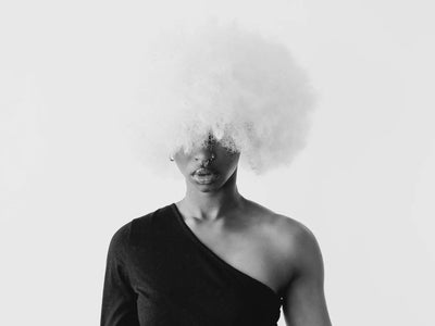 Displaying moisture - artistic black and white portrait of a woman wearing a large afro wig in a minimalistic studio setti...