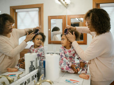 Featuring charlie's hair and beauty - a mother combs her daughter's curly hair in a cozy bathroom setting, showcasing a lo...