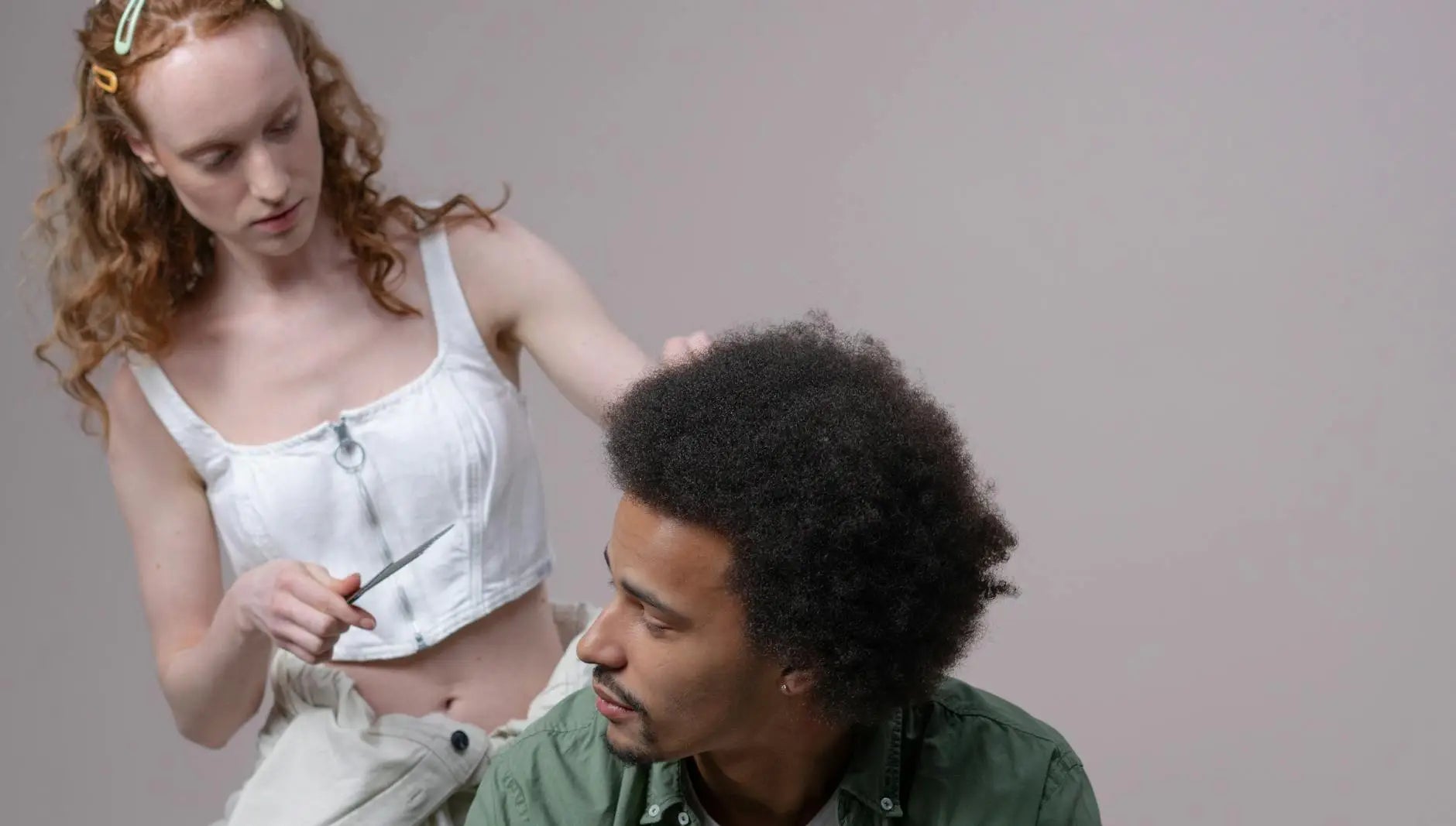 Displaying shampoo conditioner - a hairstylist working on a man's afro hair in a modern salon setting, demonstrating hairs...