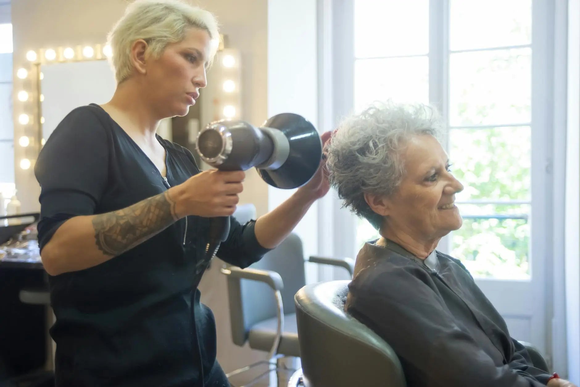 Showcasing haircut - a skilled hair stylist blow drying a senior woman's hair in a modern salon. for haircut