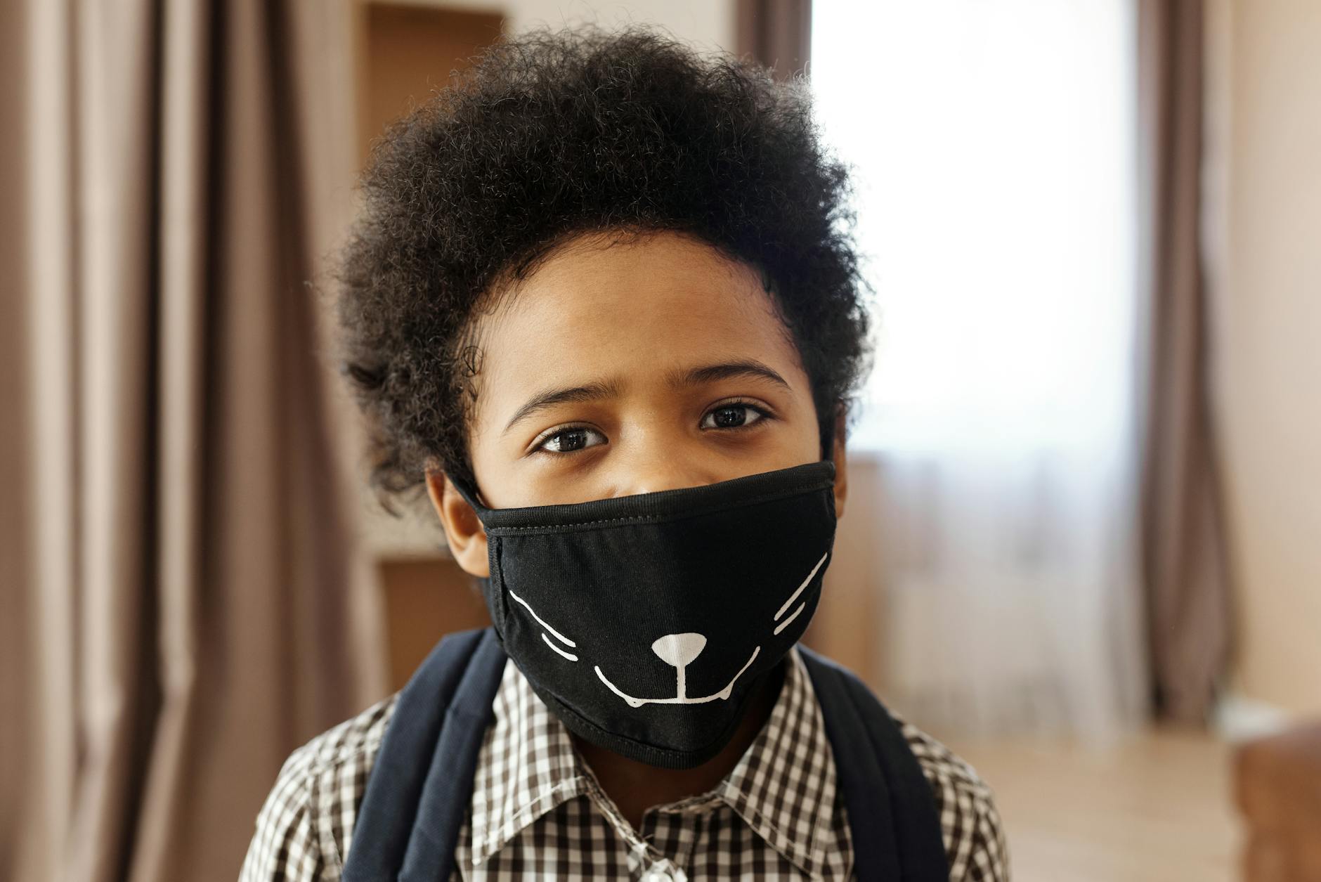 Demonstrating charlie's hair and beauty - an african american boy with an afro hairstyle wearing a creative cat-themed fac...
