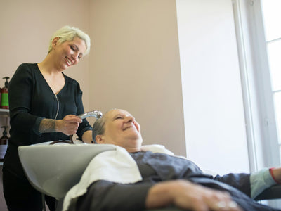 Showcasing curly - a hairdresser washes a client's hair in a modern salon in portugal, capturing a relaxed and cheerful at...