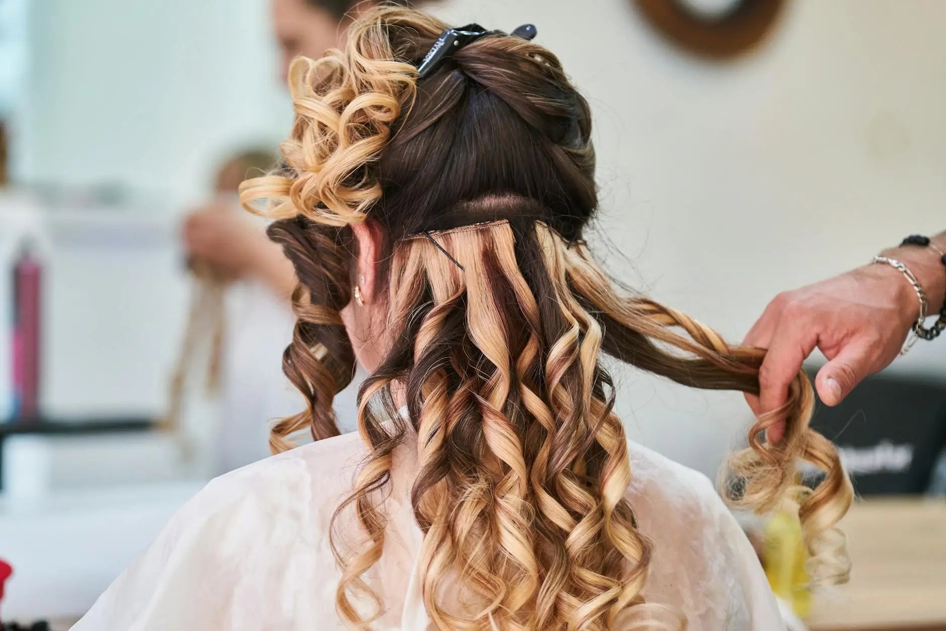 Demonstrating charlie's hair and beauty - close-up of hairstylist perfecting curls on a woman's hair in a salon setting. f...