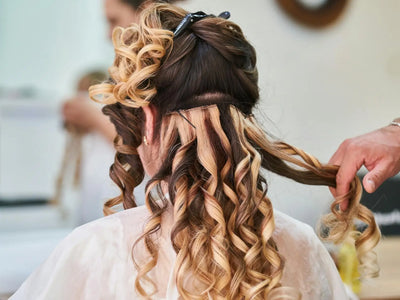 Demonstrating charlie's hair and beauty - close-up of hairstylist perfecting curls on a woman's hair in a salon setting. f...