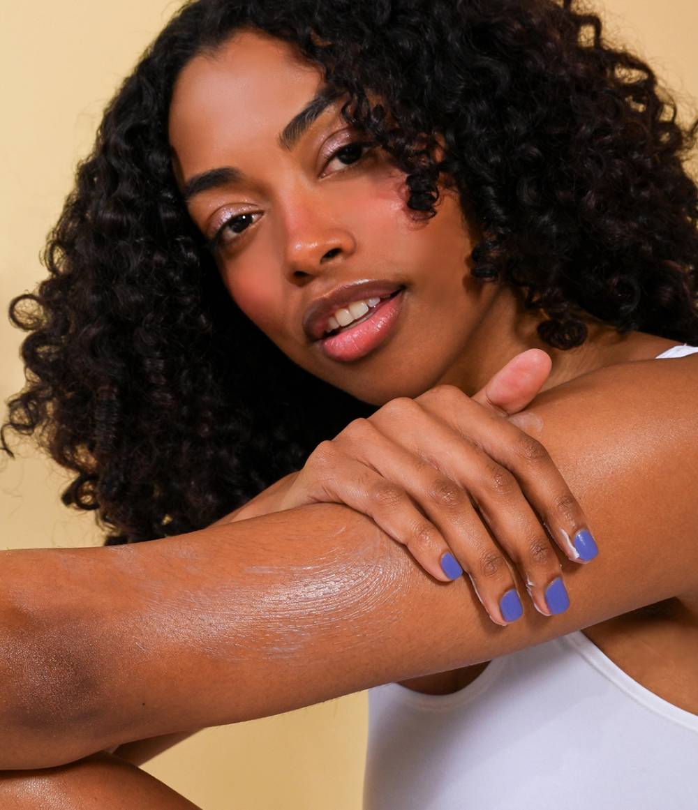 Woman with moisturized skin on arm against a beige background