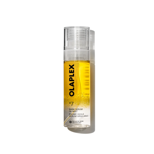 A clear cylindrical pump bottle of OLAPLEX Shine Serum Oil Mist, filled with a golden-yellow liquid, set against a plain white background with a soft shadow.