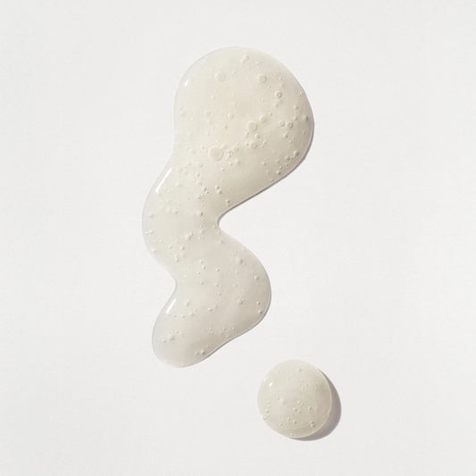 White cream or lotion with a textured surface on a light gray background