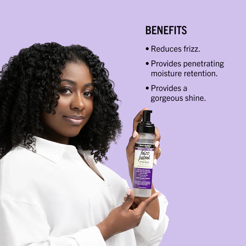 Woman holding a bottle of hair product with benefits listed on a purple background