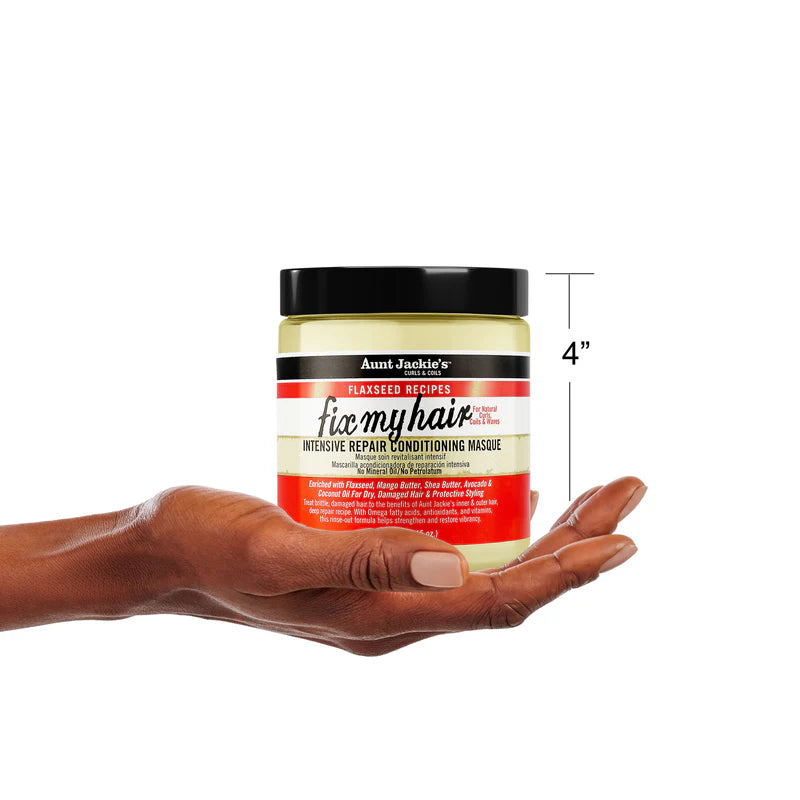 Hand holding a jar of Aunt Jackie's 'fix my hair' intensive repair conditioning masque with a white background.