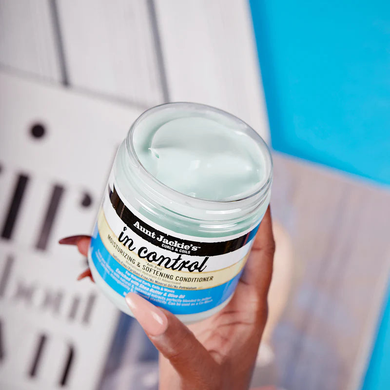 Hand holding a jar of 'In Control' conditioner with a blurred background