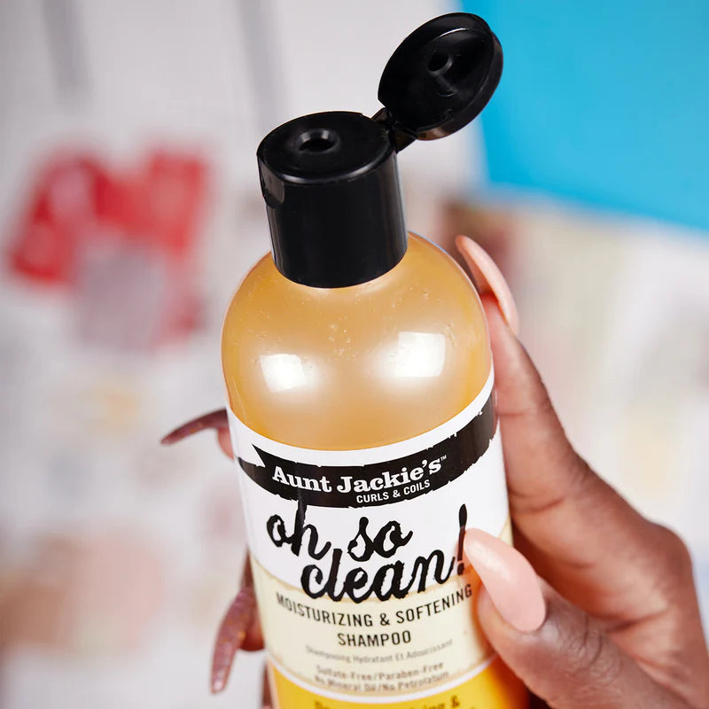 Bottle of 'Aunt Jackie's oh so clean!' shampoo held by a hand with a blurred background