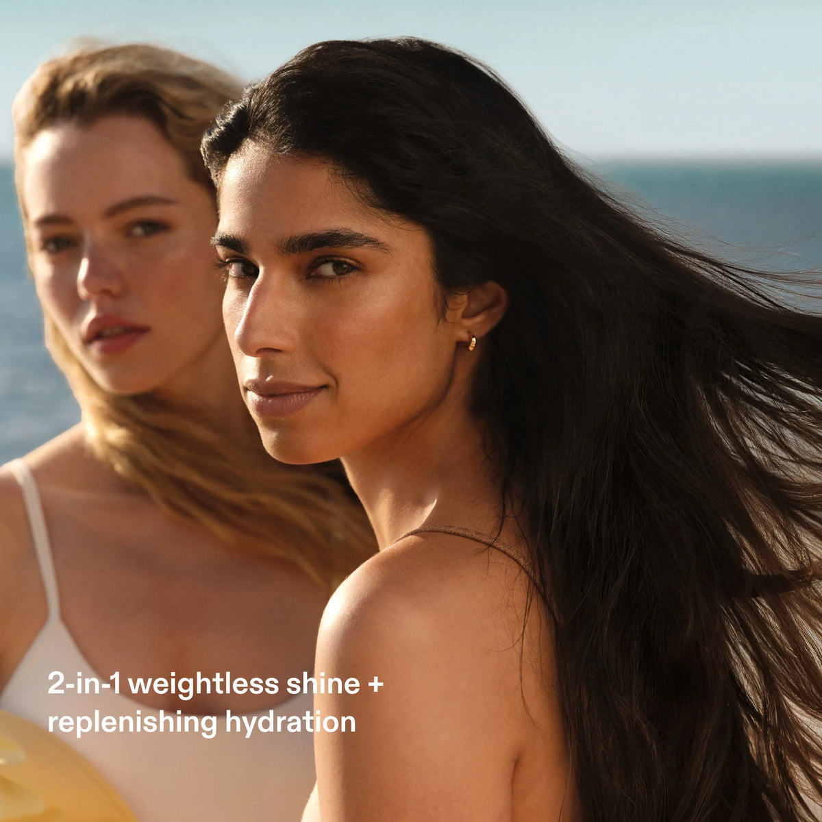 Two women with styled hair on a beach, with text about hair product features.
