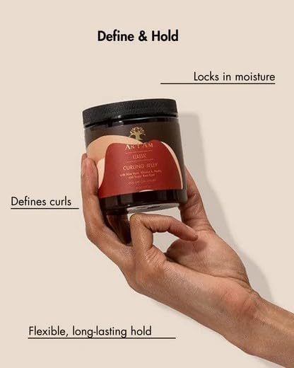 Hand holding a jar of hair product with text describing its features on a light background