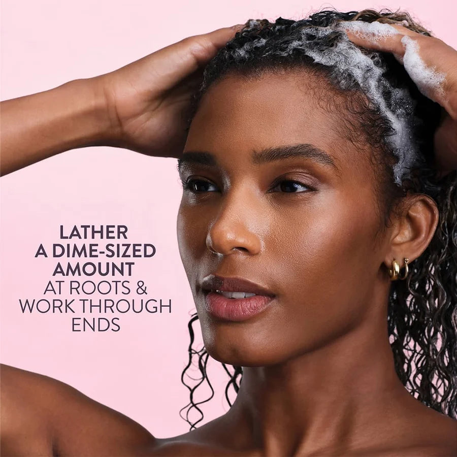 Woman with soapy hair against a pink background with text on how to use shampoo.