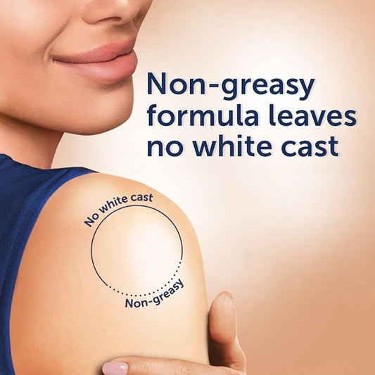 Person with 'No white cast' and 'Non-greasy' text on a tattoo, with a beige background.