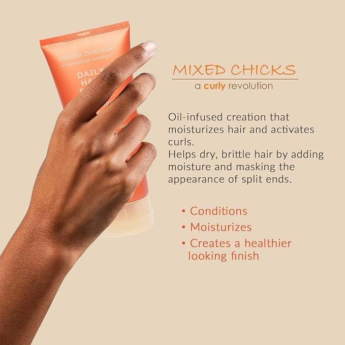 Hand holding a tube of 'Mixed Chicks' hair product with text about its benefits on a beige background.