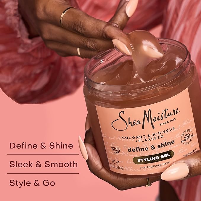 Shea Moisture styling gel jar with hand holding a spoonful of gel against a pink background