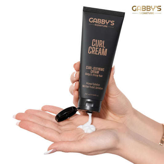 Hand holding a tube of Gabby's Signature Curl Cream with visible cream on palm