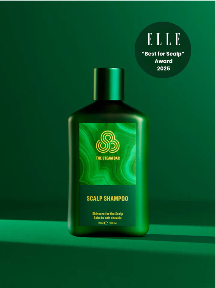 Green shampoo bottle with 'The Steam Bar' logo on a green background, featuring the 'ELLE' award text.