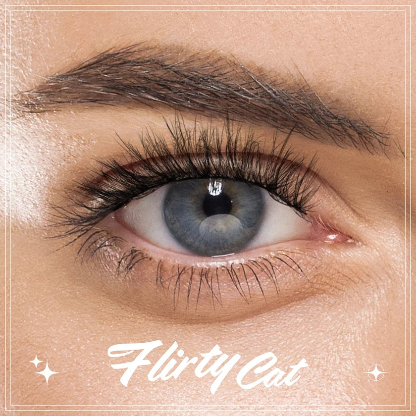 Close-up of a blue eye with long eyelashes, wearing a diamond-studded eyelash, on a beige background with 'Flirty Cat' text.