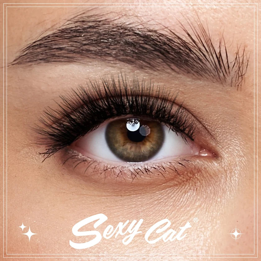 Close-up of a person's eye wearing long, dark, curled false eyelashes, with the eyebrow and surrounding skin visible. The words 'Sexy Cat' appear at the bottom.