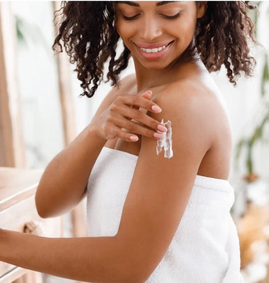 Woman applying lotion to her arm with a blurred background