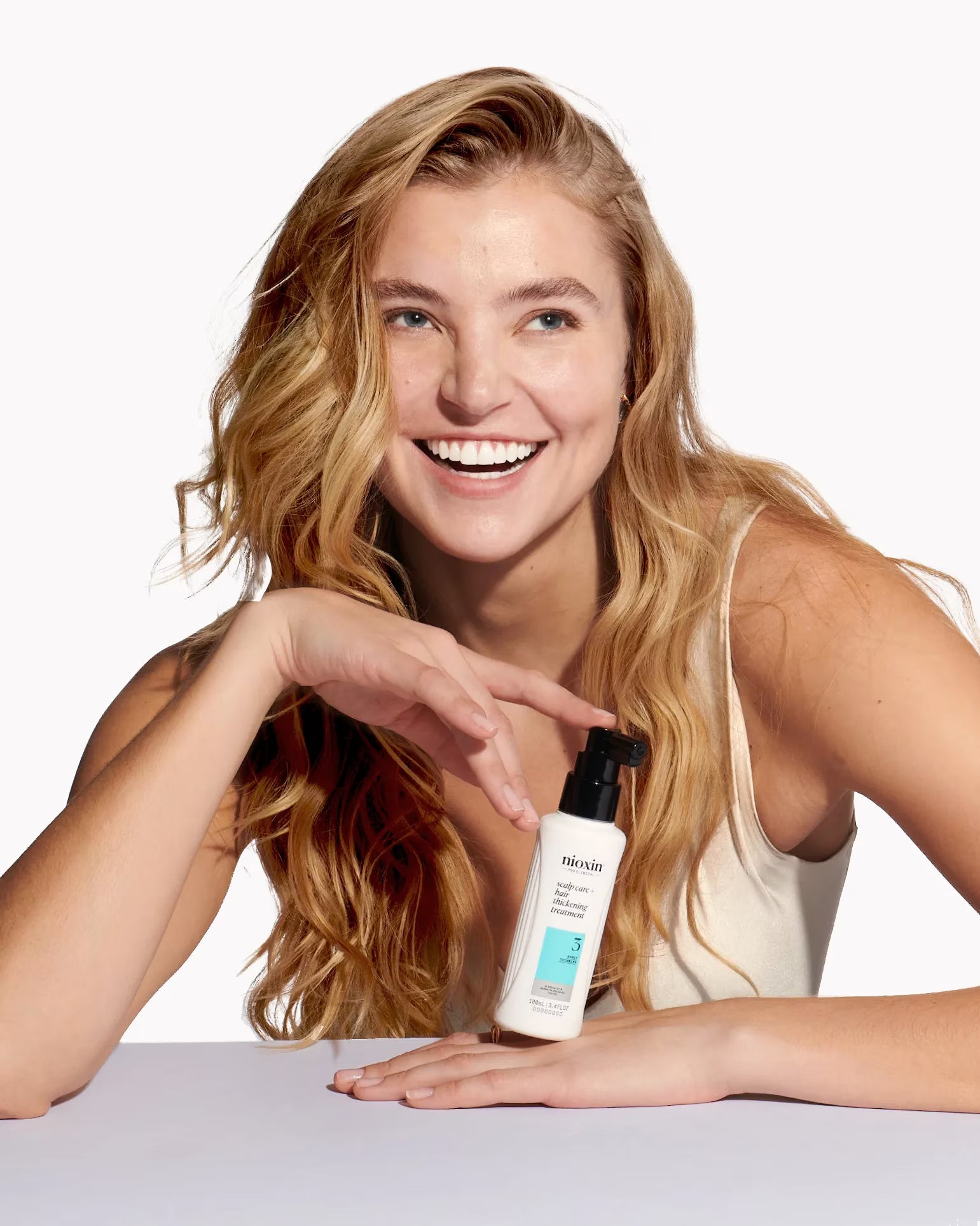 Woman holding a skincare product with a plain background