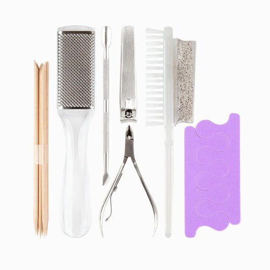 A 7-piece nail care and pedicure tool set arranged neatly on a white background. The set includes wooden nail sticks, a white hand grater, stainless steel cuticle knives and nail clippers, a white nail brush, a textured foot file, and a purple nail file guide.