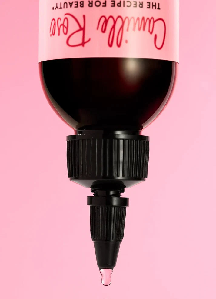 Cosmetic bottle with pink cap and black nozzle on a pink background