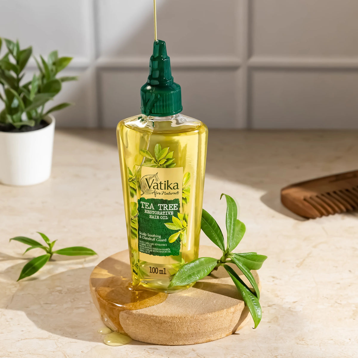 Vatika Tea Tree hair care product on a wooden stand with green leaves and a comb in the background.