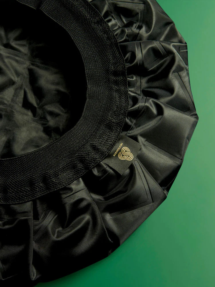 Black satin bonnet with a brand logo on a green background