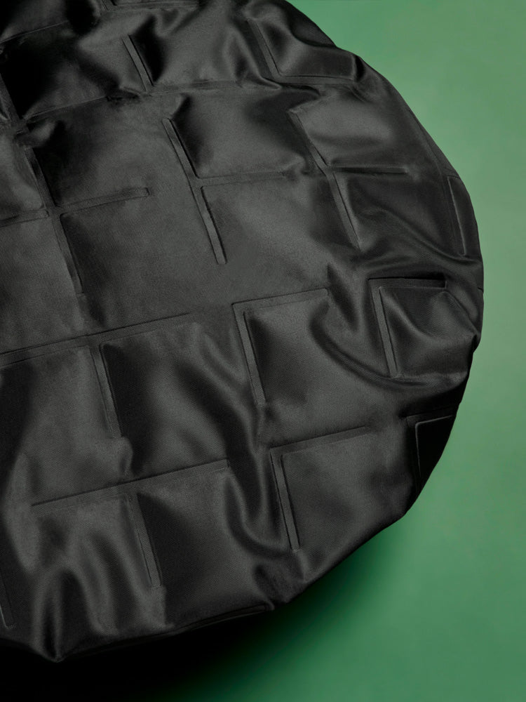 Black bag with quilted pattern on a green background