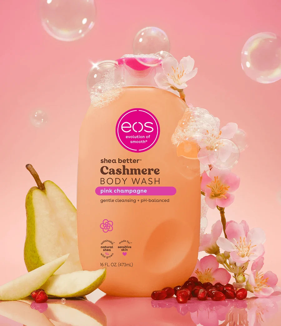 EOS shea butter cashmere body wash bottle with floral and fruit elements on a pink background