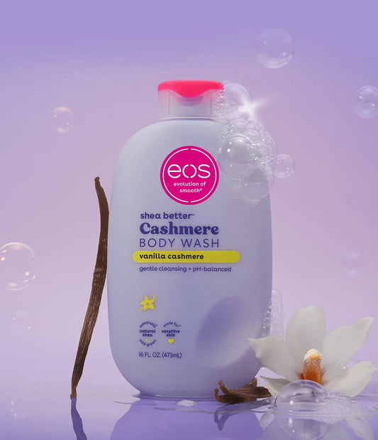 eos shea butter cashmere body wash bottle on a purple background with vanilla bean and flower.