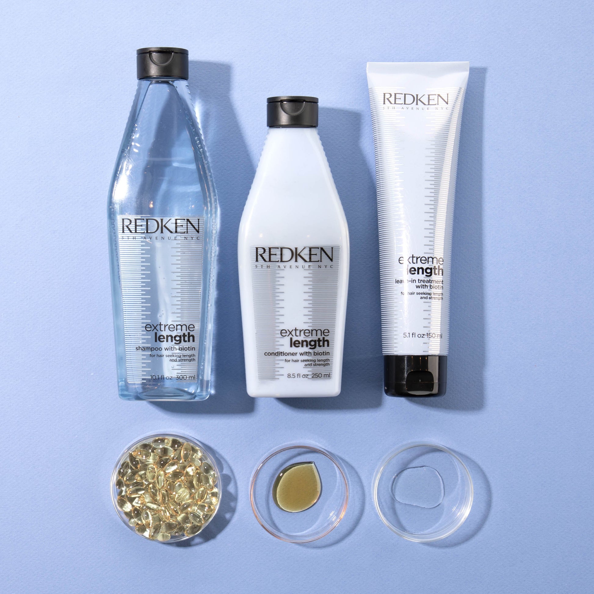 Redken hair care products including a bottle, a tube, and a jar on a blue background