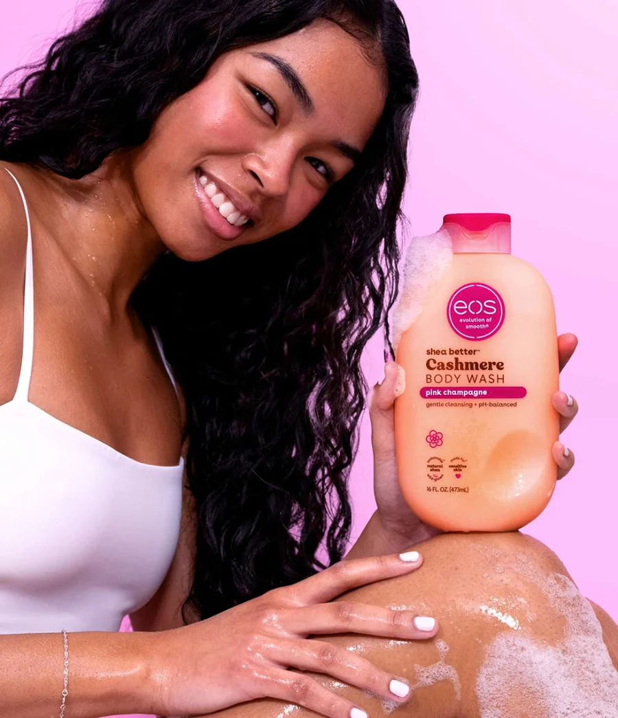 Woman holding an EOS body wash bottle with a pink background