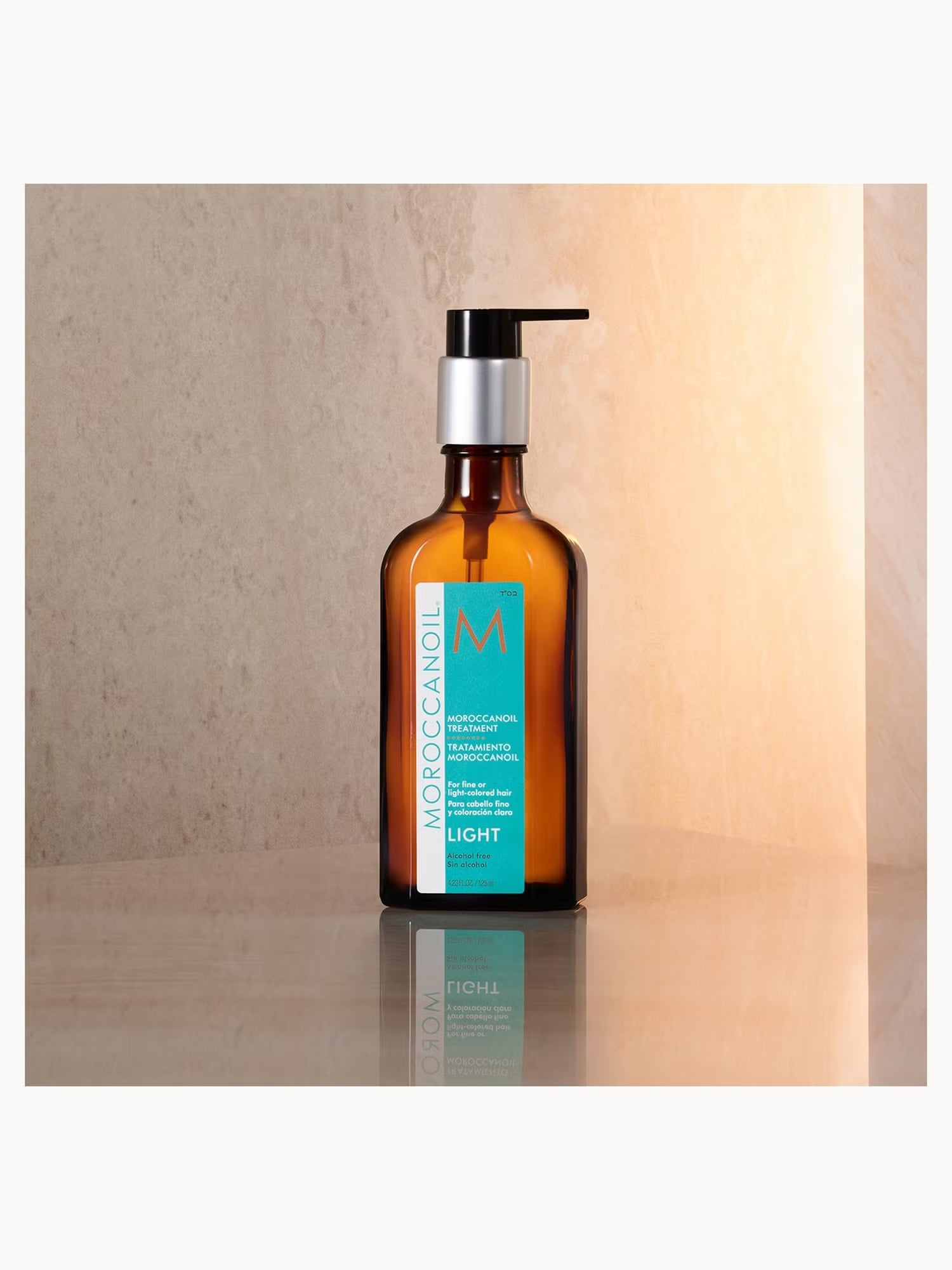 Brown bottle with pump dispenser on a reflective surface with a neutral background