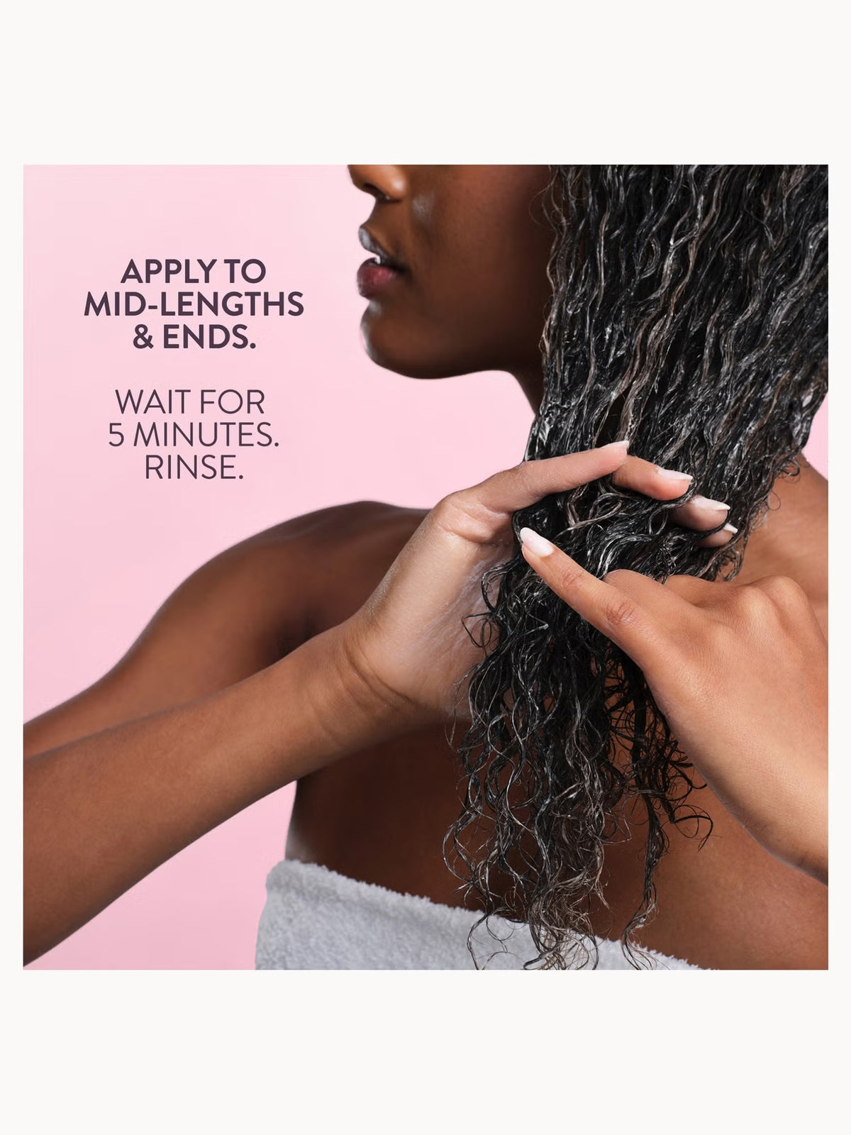 A close-up of a woman with dark curly hair applying and rinsing a hair product, with text on a pink background reading 'APPLY TO MID-LENGTHS & ENDS. WAIT FOR 5 MINUTES.