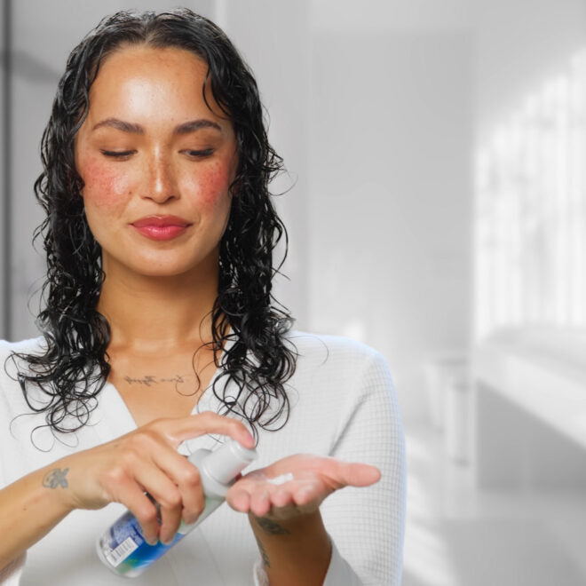 Woman applying Joico Leave in to her hands in a bathroom setting