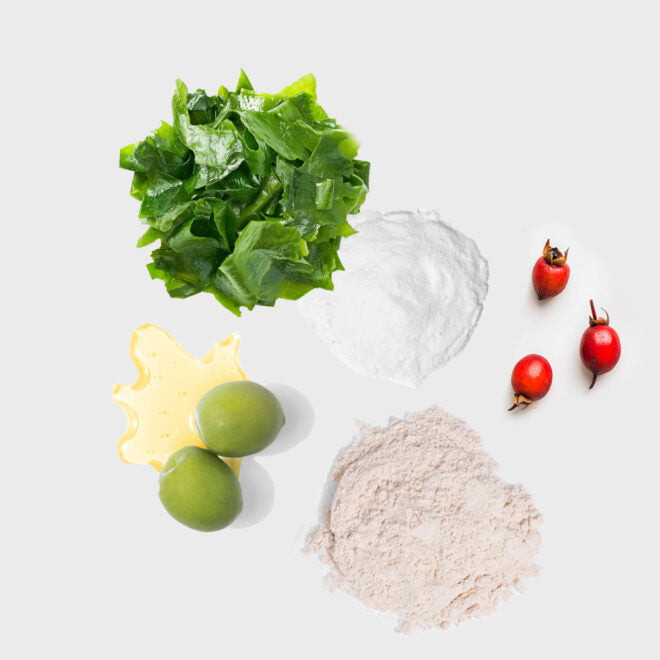 Collection of green leafy vegetables, ginger, and red berries on a light background
