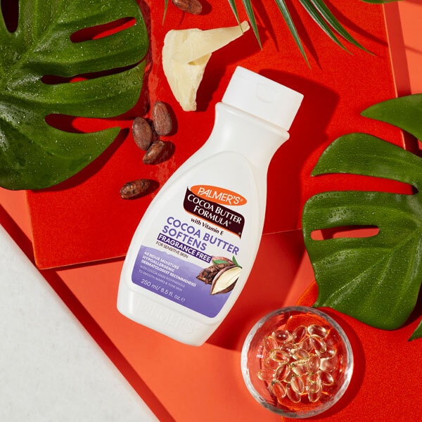 Palmer's Cocoa Butter Formula bottle on a red background with leaves and cocoa beans.