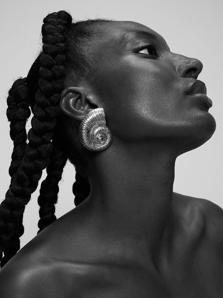 Black and white portrait of a woman with braided hair wearing a large earring.